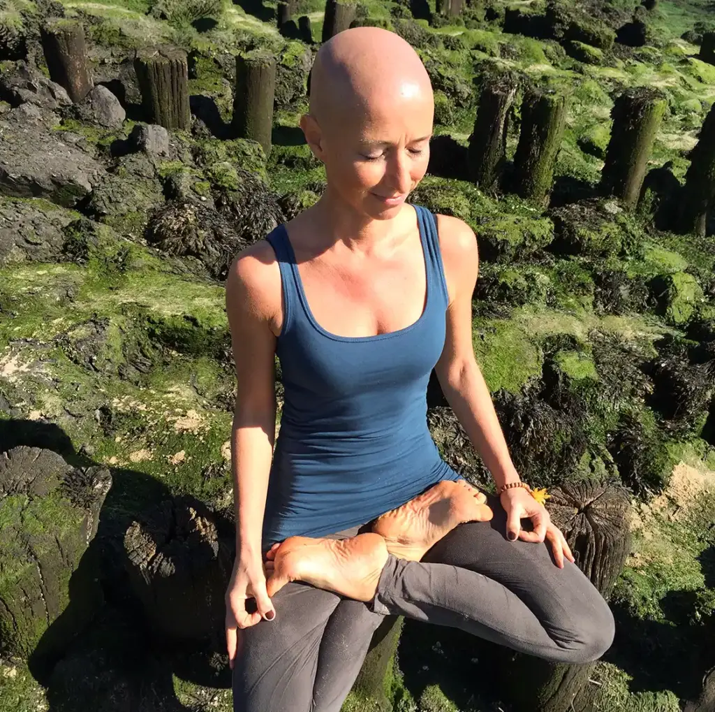 Silke Jost sitzt entspannt auf einem bemoosten Felsen in der Natur