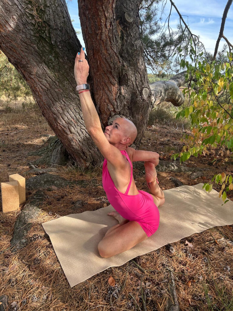 Silke Jost in einer Yogahaltung auf der Matte unter einem Baum